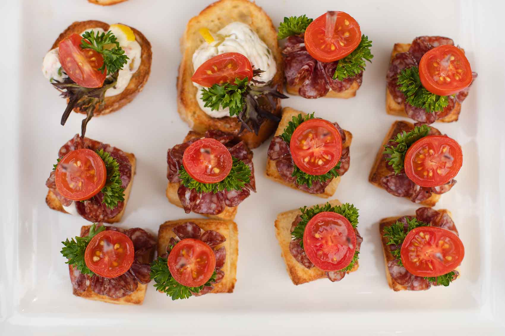 Canapes de chorizo con tomate y queso sobre plato blanco 